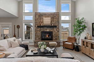 Carpeted living room featuring a high ceiling, plenty of natural light, and a fireplace