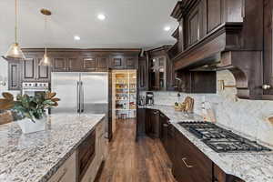 Kitchen with hanging light fixtures, stainless steel appliances, and light stone countertops