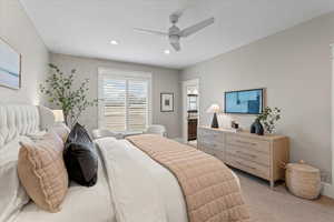 Bedroom featuring ceiling fan, connected bathroom, and light carpet