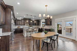 Dining room with dark wood-type flooring, a chandelier, and french doors