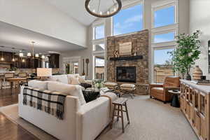 Living room featuring a healthy amount of sunlight, a fireplace, a chandelier, and light hardwood / wood-style flooring