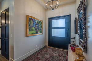 Entryway with dark hardwood / wood-style flooring and a chandelier