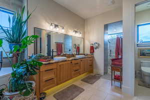 Bathroom with a shower, vanity, tile patterned floors, and toilet