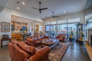 Living room featuring a stone fireplace, dark hardwood / wood-style floors, and ceiling fan