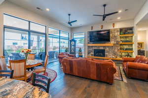 Living room with ceiling fan, a fireplace, and dark hardwood / wood-style flooring