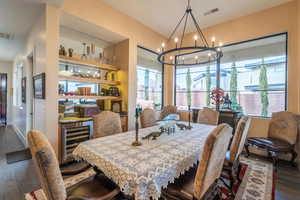 Dining area featuring bar, beverage cooler, dark hardwood / wood-style flooring, and a notable chandelier