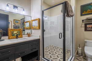 Bathroom featuring a shower with door, vanity, tile patterned floors, and toilet