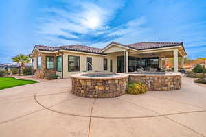 Rear view of house featuring an in ground hot tub, ceiling fan, and a patio