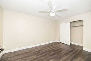 Unfurnished bedroom featuring dark wood-type flooring, ceiling fan, a closet, and a textured ceiling