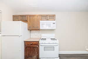 Kitchen featuring white appliances, dark hardwood / wood-style flooring, and decorative backsplash