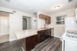 Kitchen with a breakfast bar, kitchen peninsula, white appliances, a barn door, and decorative backsplash