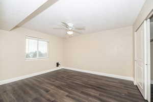 Unfurnished room with ceiling fan, dark hardwood / wood-style floors, and a textured ceiling