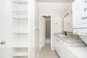 Bathroom featuring stacked washer / dryer, vanity, and tile patterned floors