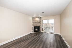 Unfurnished living room with dark hardwood / wood-style floors, a textured ceiling, and a fireplace