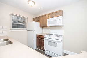 Kitchen featuring white appliances, sink, decorative backsplash, and a textured ceiling