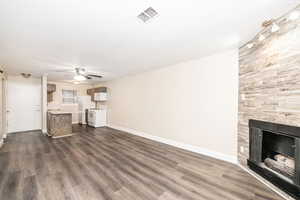 Unfurnished living room with dark wood-type flooring, ceiling fan, a fireplace, and a textured ceiling