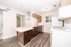 Kitchen featuring sink, decorative backsplash, a barn door, dark wood-type flooring, and white appliances