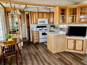 Kitchen with sink, dark hardwood / wood-style flooring, hanging light fixtures, kitchen peninsula, and white appliances