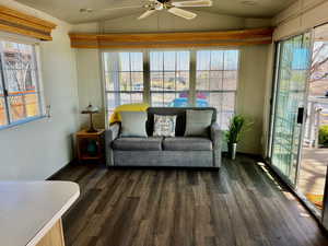 Living room with lofted ceiling, dark hardwood / wood-style floors, and ceiling fan