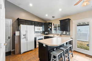 Kitchen with sink, white appliances, a kitchen breakfast bar, decorative light fixtures, and kitchen peninsula