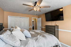 Bedroom with ceiling fan, carpet, a textured ceiling, and a closet