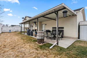 Rear view of property with a lawn and a patio area