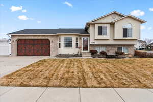 Split level home featuring a garage and a front lawn