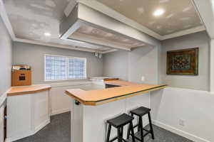 Kitchen featuring white cabinetry, crown molding, a breakfast bar area, and kitchen peninsula