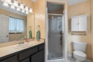 Bathroom featuring vanity, toilet, and an enclosed shower