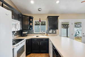 Kitchen featuring sink, hanging light fixtures, a wealth of natural light, white appliances, and backsplash