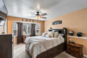 Carpeted bedroom with ceiling fan and a textured ceiling