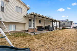 Back of property featuring a patio, a trampoline, and a lawn