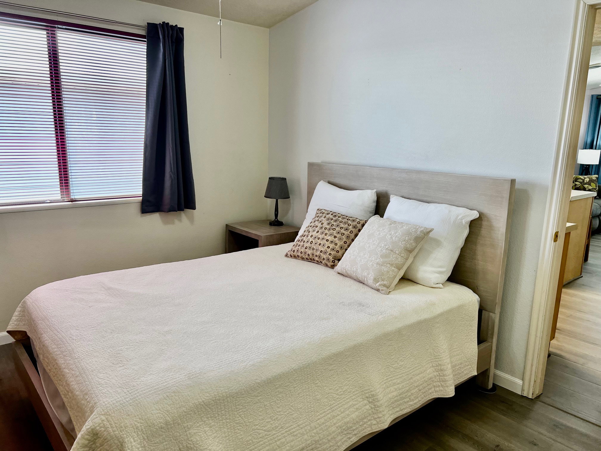 Bedroom with baseboards, multiple windows, ensuite bathroom, and wood finished floors