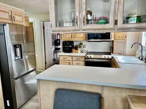 Kitchen featuring stainless steel appliances, light brown cabinetry, sink, and kitchen peninsula