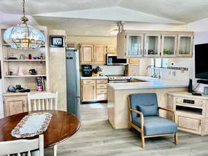 Kitchen featuring sink, decorative light fixtures, light brown cabinets, kitchen peninsula, and stainless steel appliances