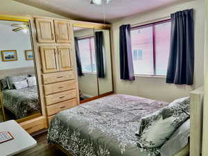 Bedroom featuring lofted ceiling, a textured ceiling, dark hardwood / wood-style flooring, and a closet