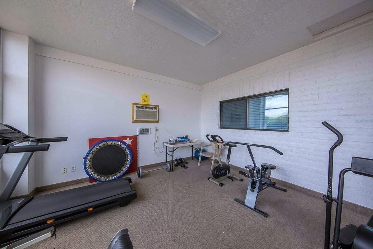 Workout room featuring a textured ceiling, a wall mounted AC, baseboards, and carpet