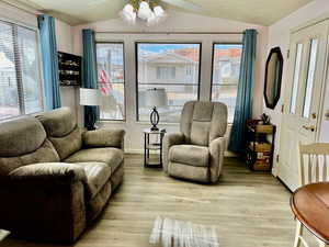 Living area featuring a wealth of natural light, vaulted ceiling, and light wood-type flooring