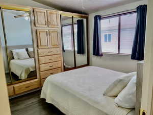 Bedroom with a textured ceiling, dark wood-style flooring, and lofted ceiling
