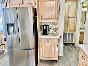 Kitchen featuring stainless steel fridge, light hardwood / wood-style floors, and light brown cabinets