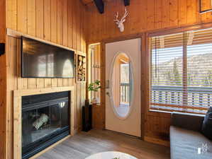 Living room with beam ceiling, wooden walls, and light hardwood / wood-style floors