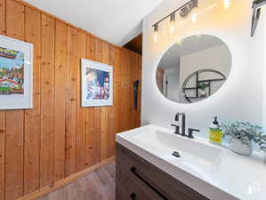 Bathroom featuring vanity, hardwood / wood-style floors, and wooden walls