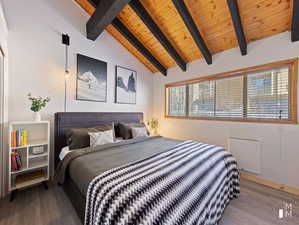 Bedroom with wood-type flooring, vaulted ceiling with beams, and wood ceiling