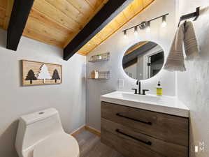 Bathroom with hardwood / wood-style flooring, vanity, lofted ceiling with beams, wooden ceiling, and toilet