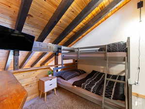 Bedroom with vaulted ceiling with beams, wood ceiling, and carpet