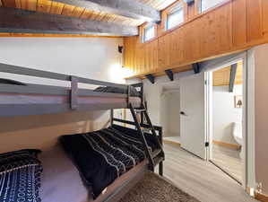 Bedroom with light wood-type flooring, wood ceiling, and beam ceiling