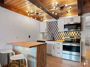 Kitchen with wood counters, beam ceiling, stainless steel appliances, and white cabinets