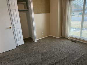 Unfurnished bedroom with dark colored carpet and a closet