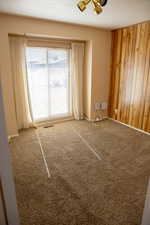 Unfurnished room with ceiling fan, carpet flooring, a textured ceiling, and wood walls