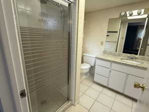 Bathroom with tile patterned floors, toilet, a shower with door, and vanity